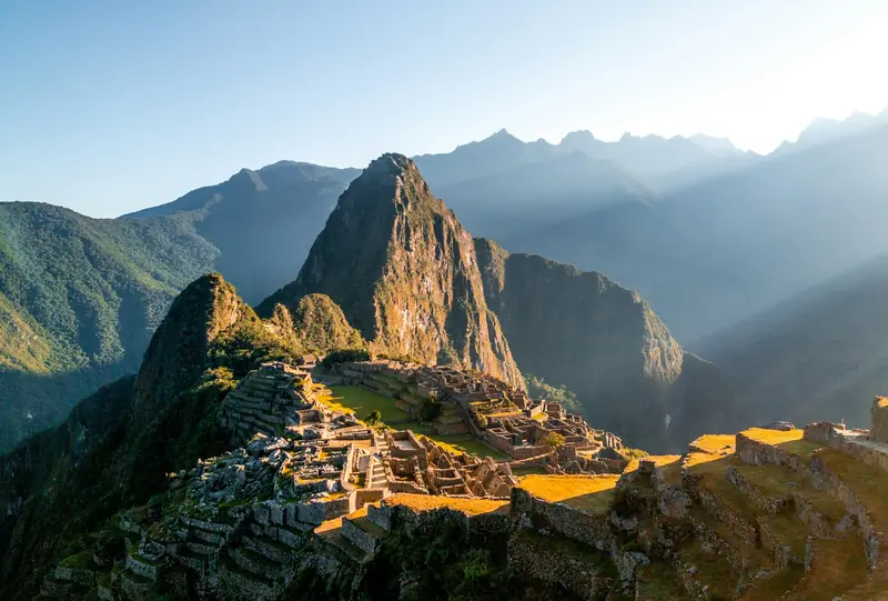 Machu Picchu al amanecer, con la luz dorada sobre la ciudadela y el Huayna Picchu